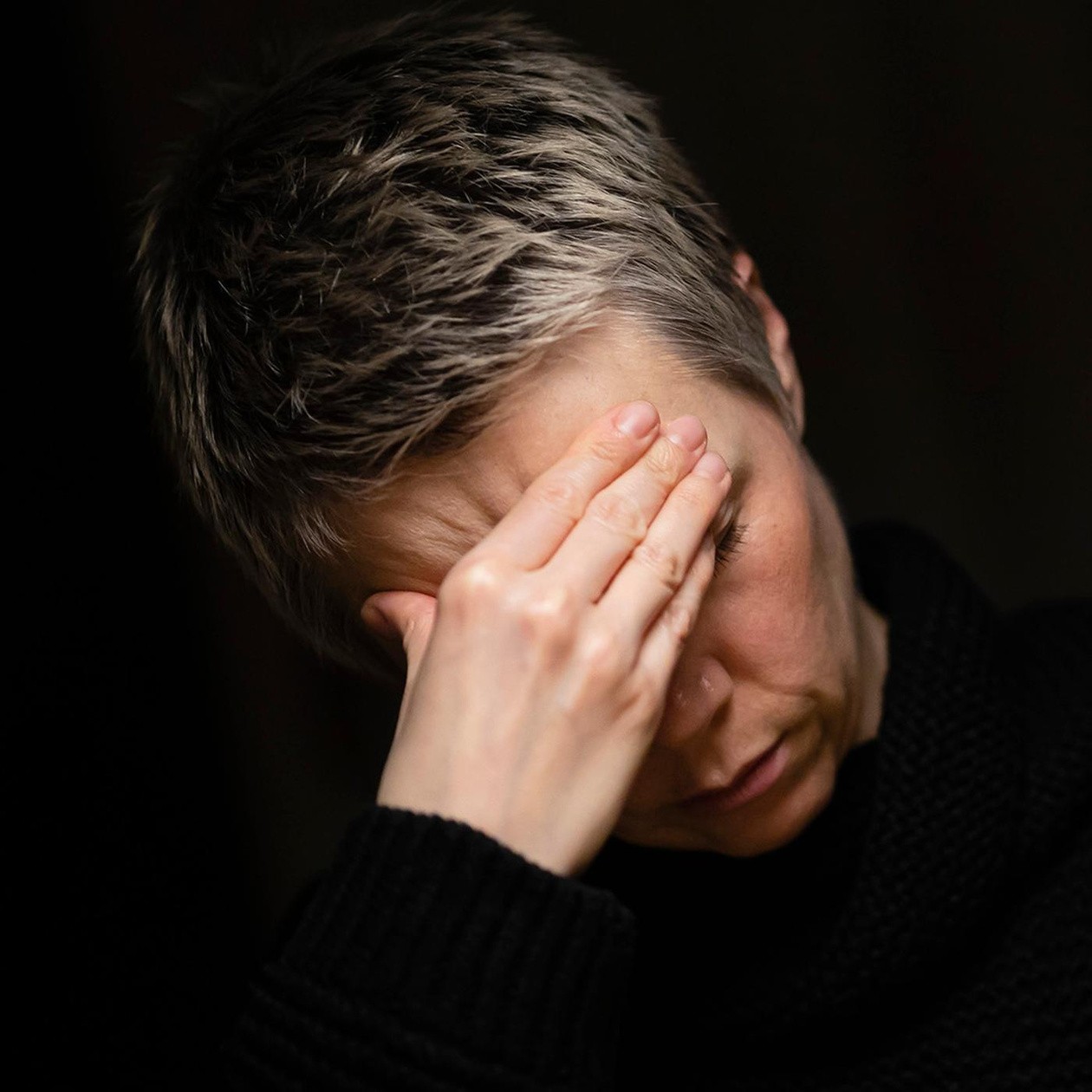 Eine erschöpfte Person hält sich die Hand an die Stirn